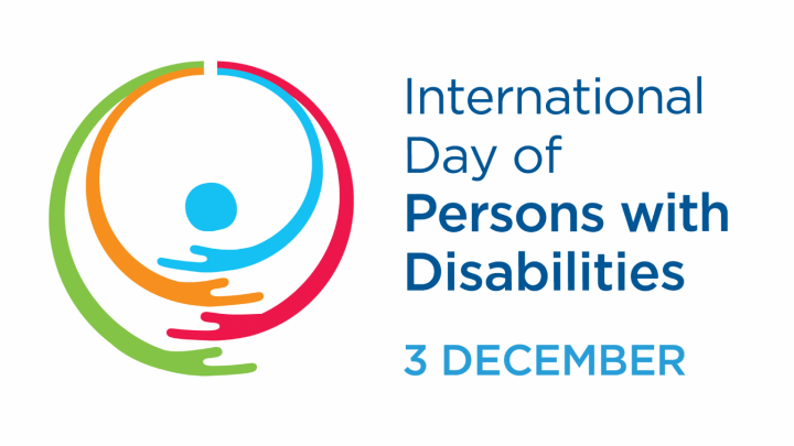 A person in the centre with blue, orange, red and green arms wrapped around them. To the left there is is the label International Day of Persons with Disabilities, that is the 3rd of December.
